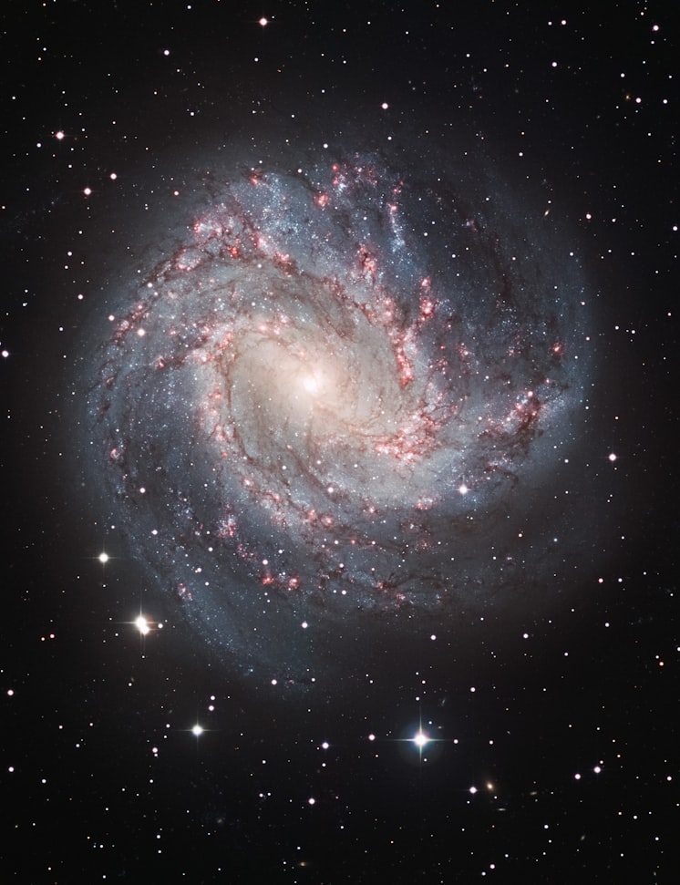 Echte Spiralgalaxie mit blauen Spiralarmen und roten Sternentstehungsregionen — astronomische Aufnahme
