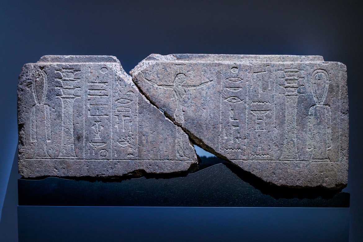 Gebrochene antike Steintafel mit Hieroglyphen — museal beleuchtet auf dunklem Hintergrund